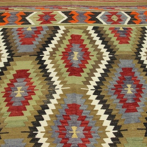May include: A traditional rug with a geometric pattern in shades of red, blue, green, brown, and white. The rug has a woven texture and a diamond-shaped design.