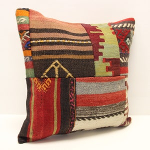 Op de afbeelding: Een kleurrijk patchwork kussen met verschillende geometrische patronen in tinten rood, bruin, groen en wit.