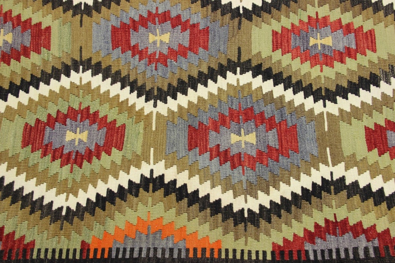 May include: A colorful rug with a geometric pattern in shades of red, green, blue, black, and white. The rug has a traditional design with repeating diamond shapes.