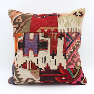May include: Square decorative pillow with a patchwork design. The pillow features a mix of colors including red, purple, orange, and cream. The patchwork design includes geometric and abstract patterns, creating a unique and textured appearance.
