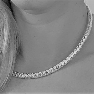 Pode incluir: Um colar de corrente de prata com um design trançado.