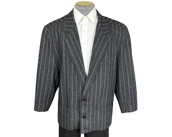 May include: A dark grey blazer featuring a subtle vertical pinstripe pattern in a lighter grey tone. The jacket has a notched lapel, two front buttons, and two lower pockets. It is worn over a crisp white button-down shirt with a classic collar.