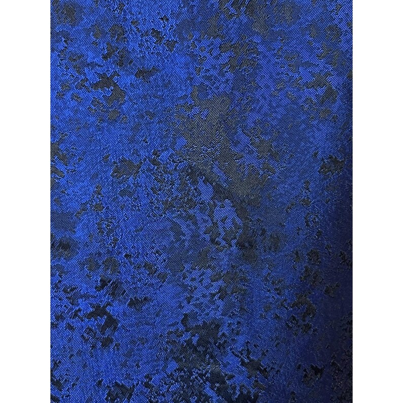 May include: A fabric textile featuring a vibrant royal blue base color with an intricate, abstract black pattern woven throughout. The material displays a subtle sheen and a textured, mottled appearance created by the contrasting dark shapes.