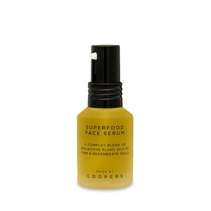 K&ouml;nnte beinhalten: Eine goldene Flasche mit schwarzer Pumpflasche und Etikett mit der Aufschrift "SUPERFOOD FACE SERUM". Das Etikett tr&auml;gt au&szlig;erdem die Aufschrift "A COMPLEX BLEND OF BIO-ACTIVE PLANT OILS TO FIRM & REGENERATE CELLS" und "MADE BY COOPERS".
