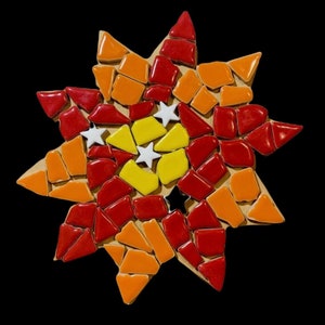 May include: A mosaic sun with red, orange, and yellow tiles. The center of the sun has a white star design.