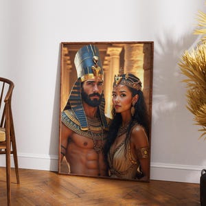 K&ouml;nnte beinhalten: Ein gerahmter Druck eines Paares, das in goldene und blaue Kleidung im &auml;gyptischen Stil gekleidet ist. Der Mann tr&auml;gt ein Kopftuch mit einer goldenen Kobra und die Frau tr&auml;gt eine Krone mit goldenen und blauen Juwelen. Der Hintergrund ist ein verschwommenes Bild eines Geb&auml;udes.
