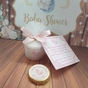 Puede incluir: Una caja de regalo rosa y blanca con una vela blanca en su interior. La caja est&aacute; decorada con una cinta rosa y un lazo de tul blanco. La caja tiene una etiqueta que dice "Paula's Baby Shower 20th June 2020". Tambi&eacute;n hay una tarjeta rosa y blanca con un poema sobre una ni&ntilde;a.