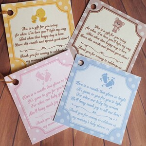 Puede incluir: Cuatro cajas de regalo con fondo blanco y lunares de colores. Cada caja tiene un color y un dise&ntilde;o diferente. Las cajas tienen un peque&ntilde;o agujero en la parte superior y una cinta atada. Las cajas tienen un poema impreso sobre ellas sobre un baby shower.