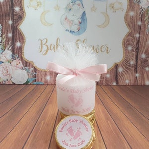 Puede incluir: Una caja de regalo rosa y dorada con un lazo de tul blanco y una cinta rosa. La caja tiene una etiqueta que dice "Baby Shower de Paula" y "20 de junio de 2020".