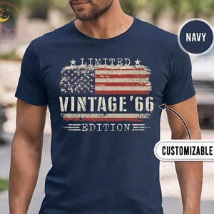 May include: Navy blue t-shirt featuring a distressed American flag design with the text "LIMITED VINTAGE '66 EDITION". The shirt is customizable and has a "NAVY" color label.