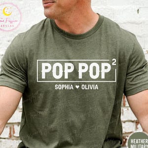 May include: Olive green t-shirt with the text "POP POP²" in a white rectangular box. Below the text are the names "SOPHIA ♥ OLIVIA". The shirt is heather military style.