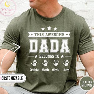 Könnte beinhalten: Olivgrünes T-Shirt mit dem Text "THIS AWESOME DADA BELONGS TO" und den Namen Sophia, Noah, Olivia und Liam. Das Shirt hat ein anpassbares Etikett und ein "HEATHER MILITARY"-Tag.