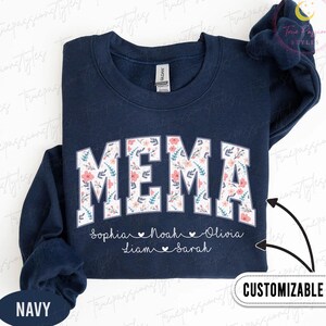 Könnte beinhalten: Marineblaues Sweatshirt mit dem Wort "MEMA" in großen, weißen Buchstaben mit floralem Muster. Darunter die Namen Sophia, Noah, Olivia, Liam und Sarah. Das Wort "ANPASSBAR" ist ebenfalls sichtbar.