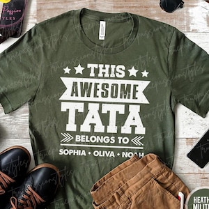 May include: Green t-shirt with white text that reads "This Awesome Tata Belongs To Sophia Olivia Noah".