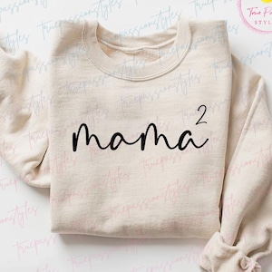 May include: A beige sweatshirt with the text "mama²" printed in black on the front.