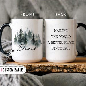 May include: White ceramic mug with a black handle and rim. The front features a watercolor forest scene with the name "David" in script. The back of the mug reads "MAKING THE WORLD A BETTER PLACE SINCE 1981".