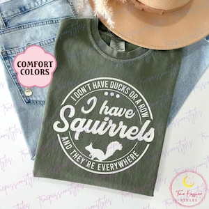May include: A green t-shirt with a white circle graphic that says "I don't have ducks or a row I have squirrels and they're everywhere".