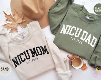 May include: Two sweatshirts, one in sand and one in heather military green, with the text "NICU MOM EST. 2025" and "NICU DAD EST. 2025" printed on them.