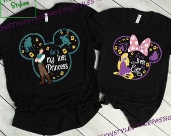 May include: Two black t-shirts with a Mickey Mouse silhouette design. One shirt features a cartoon image of Rapunzel and Flynn Rider with the text "She's my lost princess". The other shirt features a cartoon image of Rapunzel with a pink bow and the text "He's my best day ever".