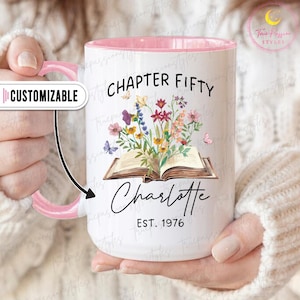 Peut inclure: Mug en céramique blanche avec intérieur et anse roses. Le mug présente le texte "CHAPTER FIFTY Charlotte EST. 1976" avec un motif floral et papillons. Le mug est personnalisable.
