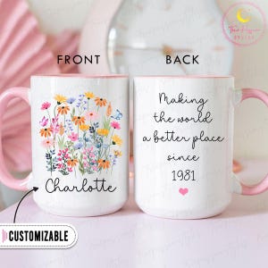 May include: A white ceramic mug with a pink handle and interior. The front features a floral design with the name "Charlotte" and the word "CUSTOMIZABLE". The back says "Making the world a better place since 1981".