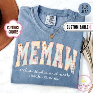 May include: Blue jean Comfort Colors t-shirt with the word "MEMAW" in a patchwork design. Below the word are the names Sophia, Olivia, Noah, Sarah, and Anna. The shirt is customizable and has a small Comfort Colors tag.