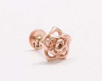 May include: A rose-gold coloured rose flower stud earring. The earring is made of metal and has a small post with a screw-on back.