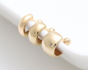 May include: Three gold hoop earrings of different sizes. The earrings are stacked on top of each other.