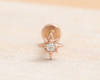 May include: A rose gold starburst stud earring with a small clear diamond in the center.