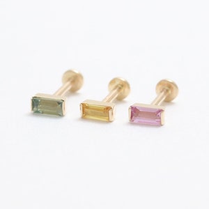 May include: Three gold stud earrings, each with a rectangular gemstone. The gemstones are green, yellow, and pink. The earrings are presented against a white backdrop. The gemstones are approximately 5mm in length.