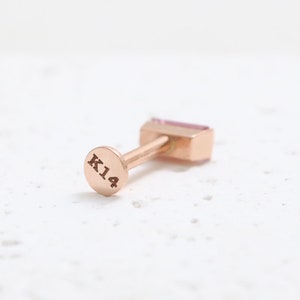 May include: A rose gold earring with a rectangular pink gemstone. The earring post has a circular backing stamped with "K14". The jewellery is set against a white background.