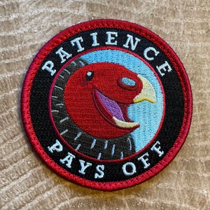 May include: Red, white, and blue embroidered patch with a cartoon bird and the text "Patience Pays Off".