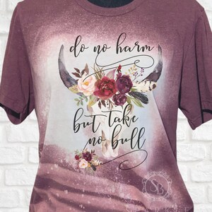 May include: A maroon t-shirt with a bleached design featuring a floral skull with the text "do no harm but take no bull".