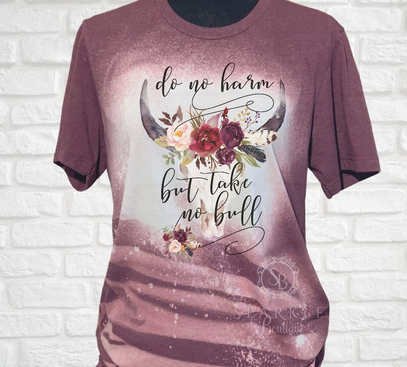 May include: A maroon t-shirt with a bleached design featuring a floral skull with the text "do no harm but take no bull".