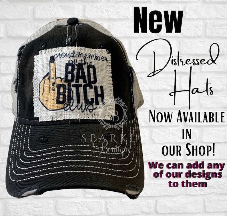 Puede incluir: Un gorro de camionero negro y blanco desgastado con un parche blanco que dice "Proud Member of the Bad Bitch Club" con un emoji de dedo medio. El gorro es nuevo y est&aacute; disponible en la tienda.