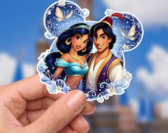 May include: A sticker featuring a cartoon illustration of Aladdin and Princess Jasmine. The sticker has a blue and white background with a Mickey Mouse ear shape. Jasmine wears a teal top and gold jewelry. Aladdin wears a purple vest and a red hat.