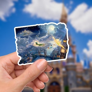 May include: A sticker featuring a whimsical illustration of Peter Pan, Tinkerbell, and other characters flying over London at night. The artwork includes the London Bridge, Big Ben, and a castle in the distance, set against a cloudy sky.
