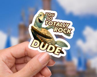 Puede incluir: Una pegatina con una tortuga marina de dibujos animados y el texto "YOU SO TOTALLY ROCK DUDE". La tortuga es de color verde claro y marrón, con una expresión sonriente. El fondo es una imagen borrosa de un castillo y un cielo azul.
