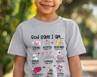 May include: A gray short-sleeved t-shirt with a colorful Easter-themed design. The text on the shirt reads "God says I am..." and lists positive attributes like "strong", "accepted", "redeemed", "bold", "capable", "protected", "courageous", "kind", and "loyal".