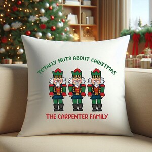 May include: White throw pillow with a festive design featuring three nutcracker figures and the text "Totally Nuts About Christmas The Carpenter Family".
