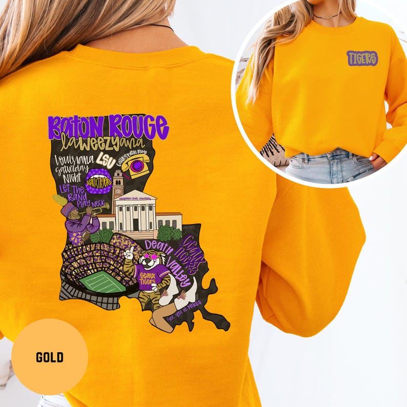 May include: Gold sweatshirt with a graphic of the Louisiana state outline, featuring text and illustrations related to Baton Rouge and LSU. The sweatshirt has the word "Tigers" on the upper right chest.