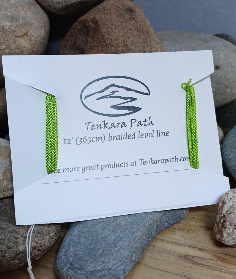 Puede incluir: Una l&iacute;nea de pesca trenzada verde empaquetada en una tarjeta blanca con el texto "Tenkara Path 12' (365cm) braided level line" y la direcci&oacute;n del sitio web "Tenkarapath.com".