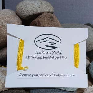 Puede incluir: Una tarjeta blanca con una l&iacute;nea de pesca trenzada amarilla. La tarjeta tiene el texto "Tenkara Path" y "12' (365cm) braided level line". La tarjeta tambi&eacute;n tiene un logotipo de una cordillera con un r&iacute;o que la atraviesa. El texto "See more great products at Tenkarapath.com" est&aacute; en la parte inferior de la tarjeta.