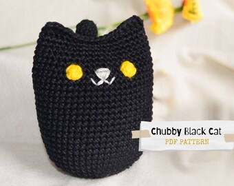 May include: A handmade, black crochet cat with yellow eyes and white embroidered details. The cat has a rounded shape and a small tail. Text on the image reads "Chubby Black Cat PDF Pattern".