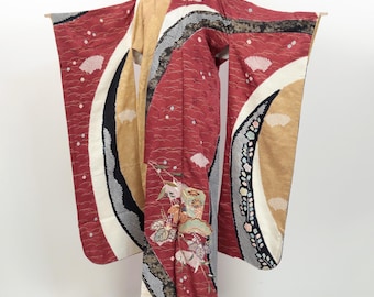 May include: A traditional Japanese kimono with a red, gold, and black design. The kimono features a large, curved pattern with floral motifs and a geometric design.