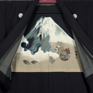 Könnte beinhalten: Schwarzer Kimono mit einem lebendigen Innendesign, das eine Berglandschaft zeigt. Das Kunstwerk umfasst einen schneebedeckten Berg, Wolken und dekorative Elemente in Blau, Beige und Braun. Der Kimono hat weiße runde Knöpfe.