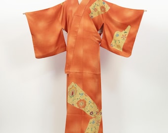 May include: An orange kimono with floral detailing. The garment displays a gradient effect, shifting from a lighter tone at the top to a darker shade at the base. Gold, red, and blue floral patterns decorate the sleeves and lower section of the kimono.