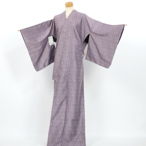 May include: A full-length kimono in a muted mauve-purple hue featuring an all-over repeating pattern of small, light-colored vertical dashes. The garment has wide, extended sleeves and a structured collar, displayed on a mannequin form.
