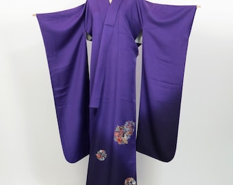 May include: A striking purple kimono with long sleeves. The fabric displays a colour gradient, fading from a lighter shade at the top to a darker tone at the hem. The lower section is embellished with floral embroidery, adding a decorative element to the traditional garment.