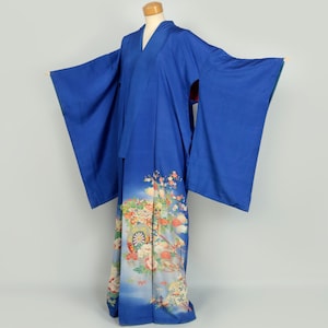May include: A blue kimono with a floral pattern on the bottom half. The kimono is on a mannequin and has long sleeves.